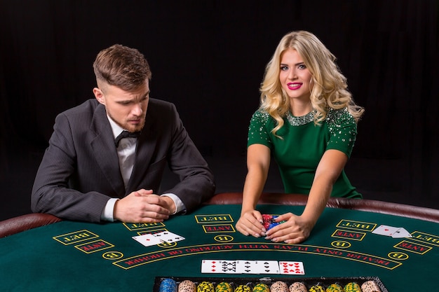 Couple jouant au poker à la table verte. La fille blonde et un gars en costume. bonne victoire