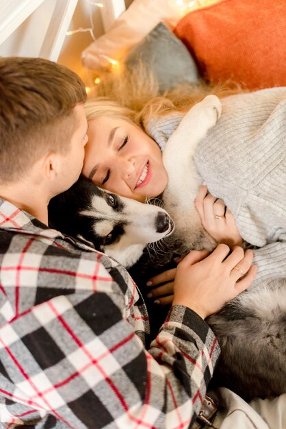 Photo couple jouant avec un chien dans la chambre