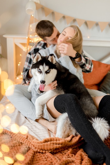 Couple jouant avec un chien dans la chambre