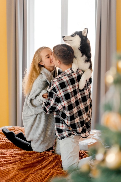 Couple jouant avec un chien dans la chambre