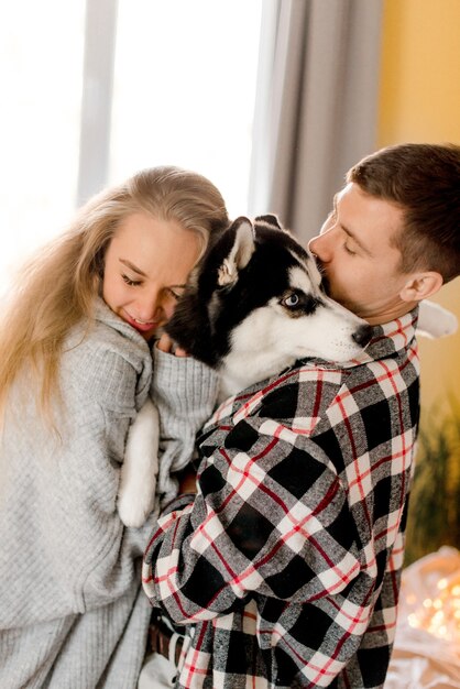 Photo couple jouant avec un chien dans la chambre