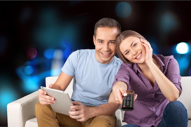 Un couple joyeux choisissant une émission de télévision sur une tablette numérique