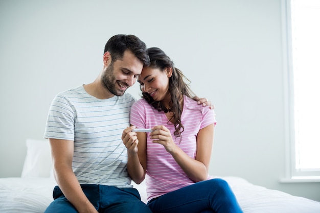 Couple joyeux découvrant les résultats d'un test de grossesse dans la chambre à coucher à la maison