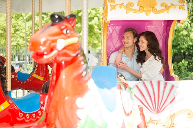 Couple joyeux s&#39;amuser sur un carrousel