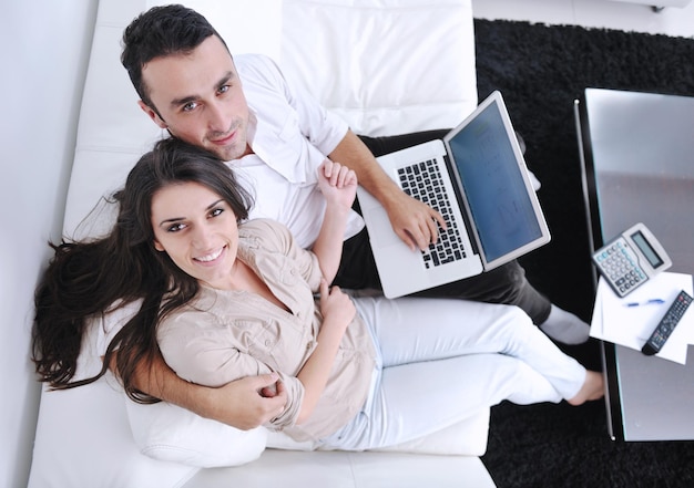 un couple joyeux se détend et travaille sur un ordinateur portable dans la maison intérieure du salon moderne