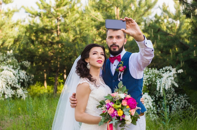 Couple juste marié faisant selfie dans le parc