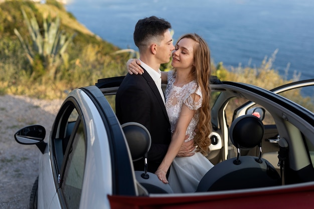 Photo couple juste marié à l'intérieur d'une petite voiture