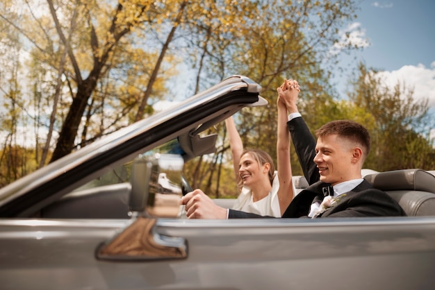 Photo couple juste marié avec leur voiture