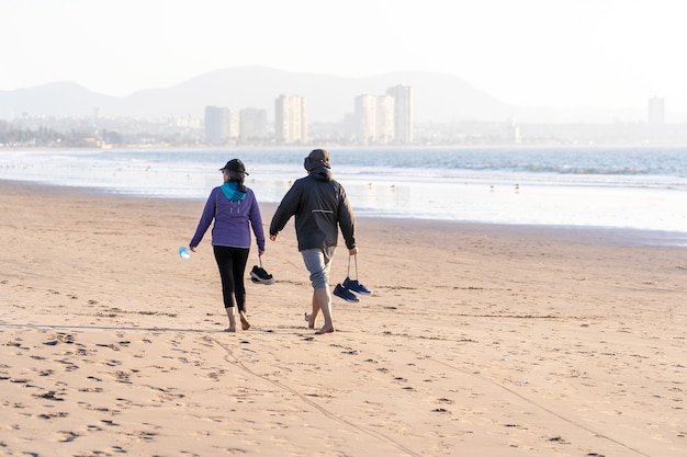 couple latin marchant pieds nus sur la plage de La Serena