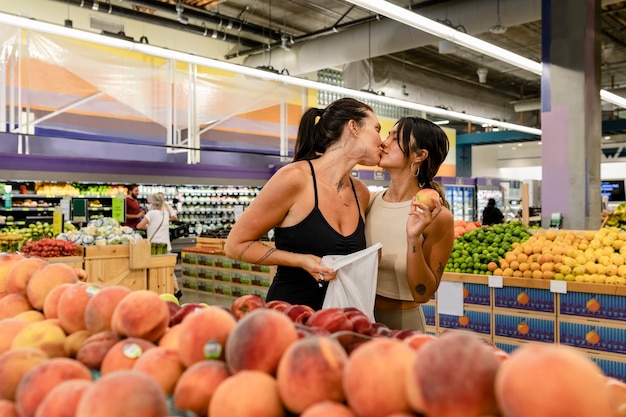 Couple de lesbiennes espiègles faisant du shopping, s'embrassant dans un supermarché