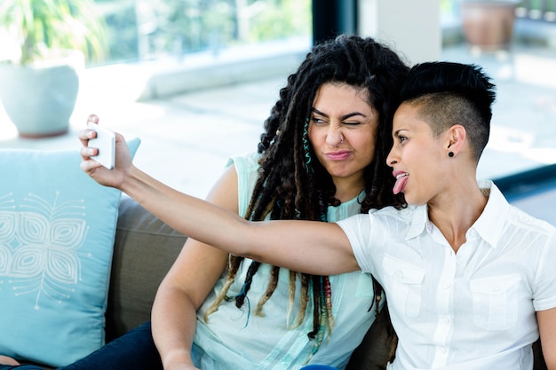 Couple de lesbiennes prenant un selfie au téléphone dans le salon