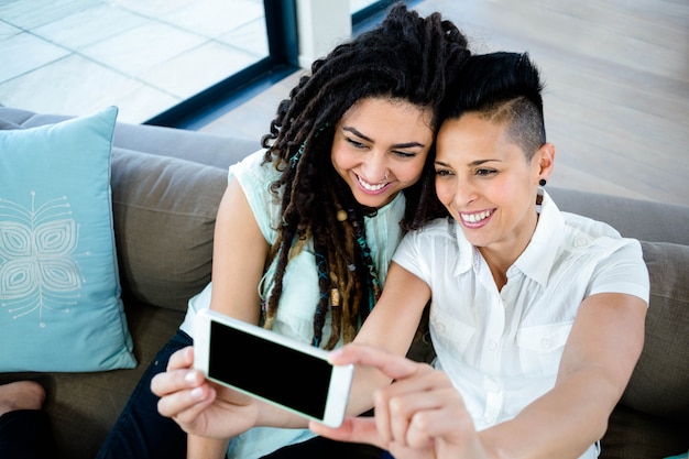 Couple de lesbiennes prenant un selfie au téléphone dans le salon