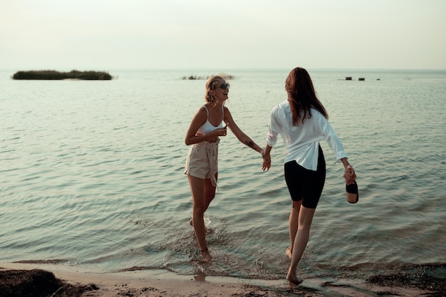 Couple de lesbiennes s'amuser sur la plage Belles femmes amis heureux se détendre près de la mer