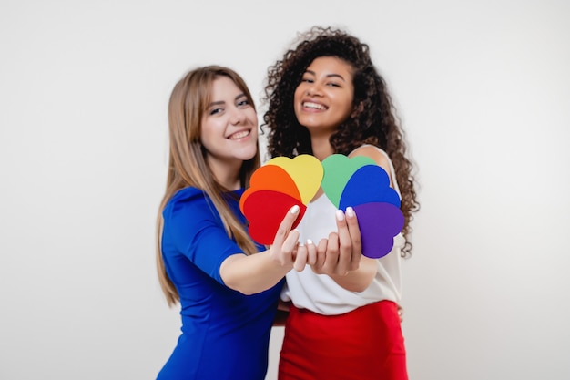 Couple de lesbiennes tenant des formes de coeur de couleurs lgbt isolés