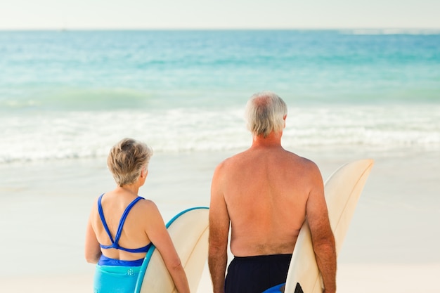 Couple avec leur planche de surf sur la plage