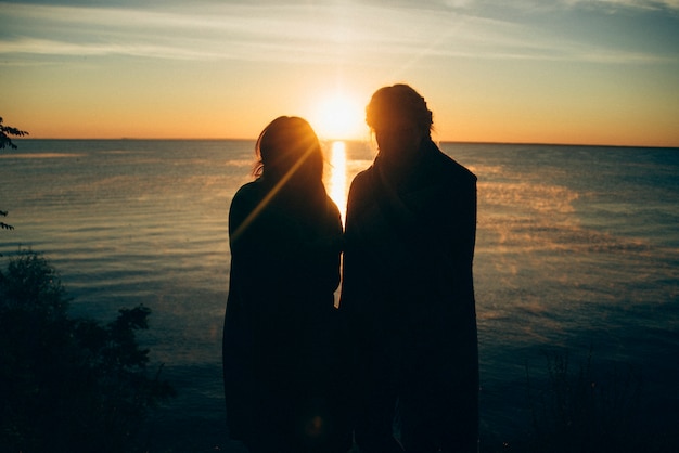 Couple, à, levers de soleil, sur, bord mer