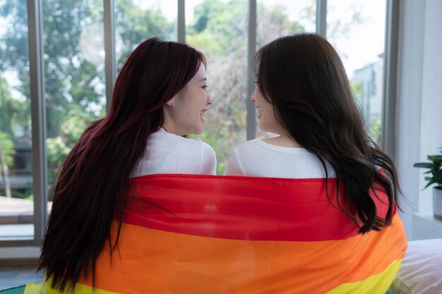 Le couple LGBT était assis sur le lit couvert de drapeaux arc-en-ciel et regardait par la fenêtre pour observer la nature.