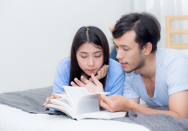 Couple lisant un livre ensemble dans la chambre le matin avec bonheur.