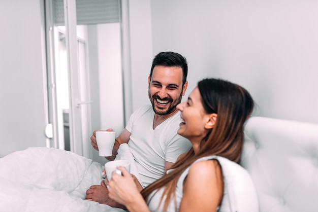 Couple, lit, boire café, rire