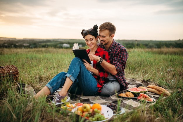 Couple lit livre ensemble, pique-nique sur le terrain