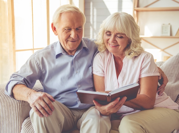 Couple lit un livre et souriant assis sur un canapé