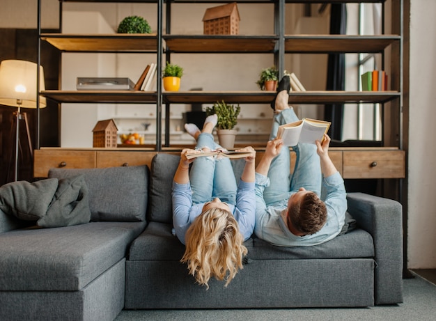 Couple avec des livres allongés sur le canapé à l'envers