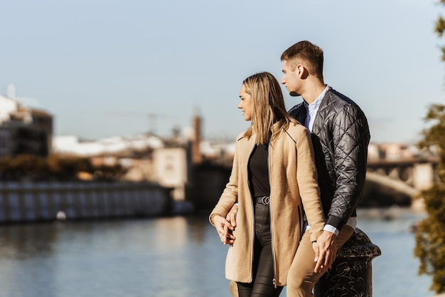 Couple main dans la main alors qu'ils regardent au-dessus d'une rivière dans une ville