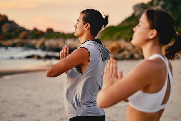 Couple mains de prière et méditation de yoga à la plage en plein air pour la santé et le bien-être Fitness pilates au coucher du soleil et homme et femme avec la pose de la main namaste pour l'entraînement à la paix calme et à l'exercice de pleine conscience