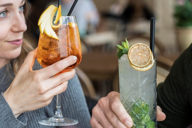 Couple mains toasting spritz et mojito Jeunes amis s'amusant ensemble en buvant des cocktails à l'happy hour Premier concept de temps de rencontre