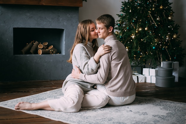 Couple à la maison au moment de Noël près de l'arbre de Noël joliment décoré