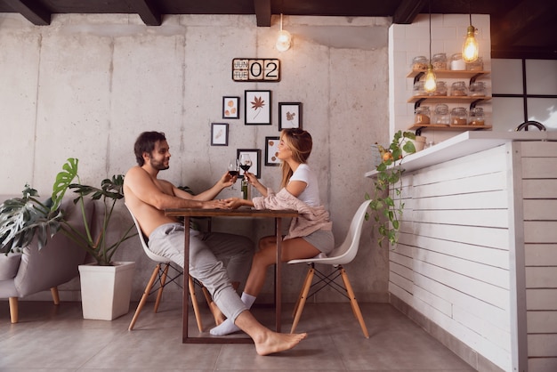 Couple à la maison souriant et tenant des verres à vin