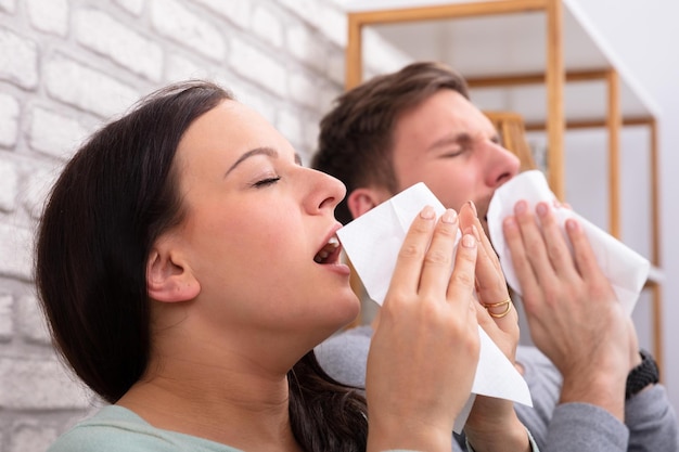 Couple malade éternuant dans un tissu