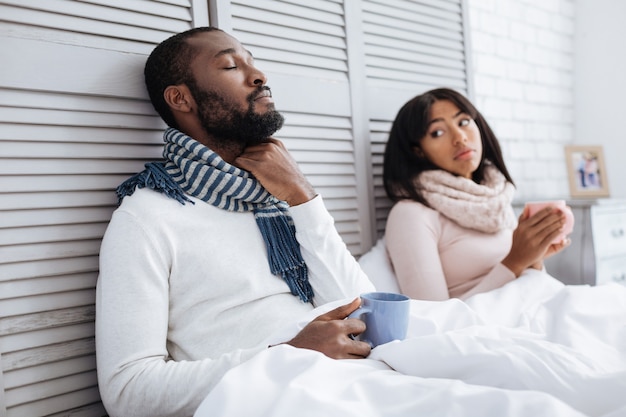 Couple malade. Fatigué de couple agréable d'être au lit avec des tasses de thé tout en se remettant de la grippe ensemble