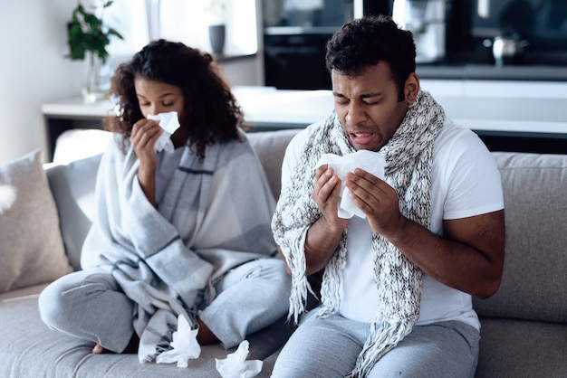 Couple de maladie avec température assis sur un canapé