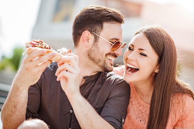 Couple mangeant une collation de pizza à l'extérieur