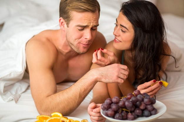 Couple mangeant des fruits au lit.