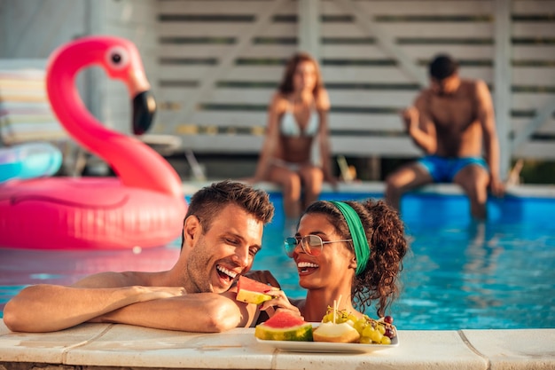 Couple mangeant des fruits à la piscine