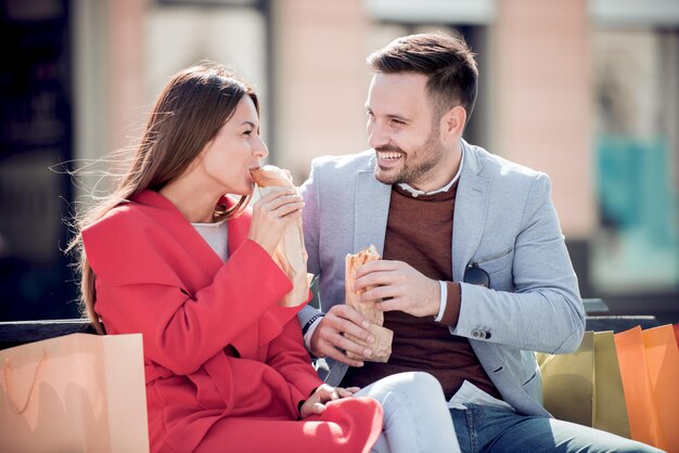 Couple mangeant des sandwichs après le shopping