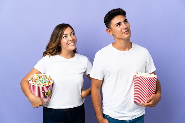 Couple de manger du pop-corn tout en regardant un film sur le violet en levant en souriant