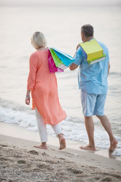 Couple marchant sur la plage après les achats de vacances