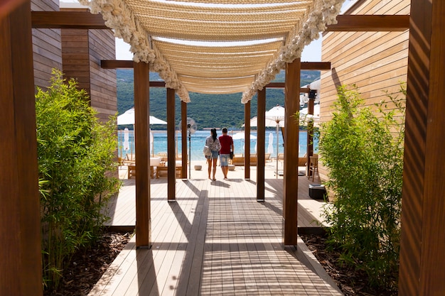 Un couple marche sur une terrasse en bois à travers un café de plage à la mer Adriatique