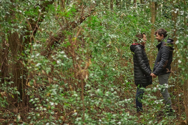 Couple de mariage d'âge moyen se tenant la main et se regardant dans les yeux dans la forêt. Ils portent un manteau en hiver. Caucasiens.