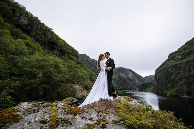 Couple de mariage debout sur un rocher, dans le contexte de la rivière