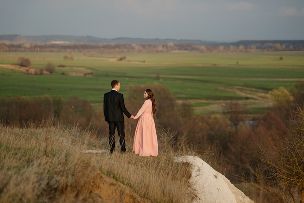 Photo couple de mariage heureux admirer le magnifique paysage au coucher du soleil.