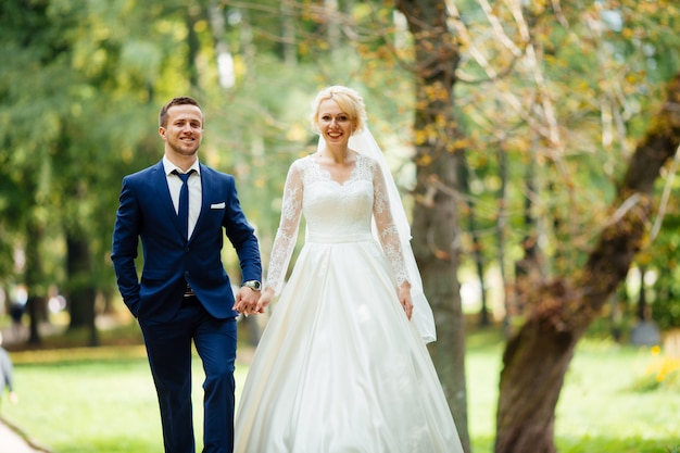 Couple de mariage heureux marchant dans le parc