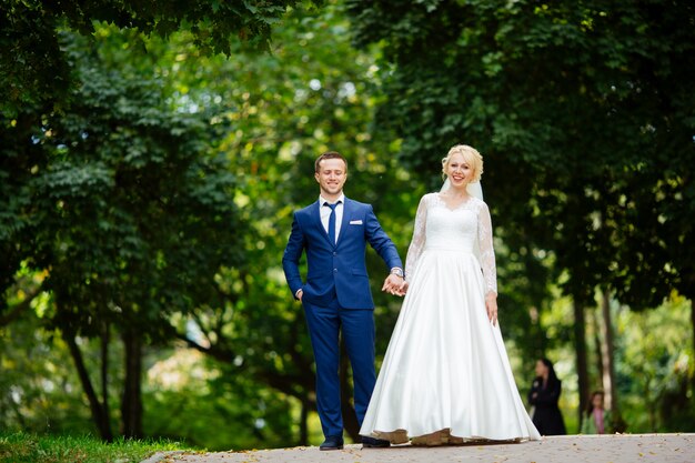 Couple de mariage heureux marchant dans le parc