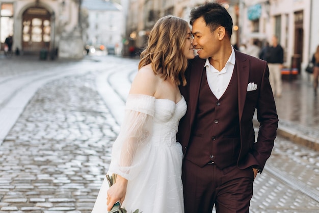 Un couple de mariage international, une mariée européenne et un marié asiatique, se promènent ensemble dans la ville