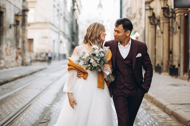 Un couple de mariage international, une mariée européenne et un marié asiatique, se promènent ensemble dans la ville