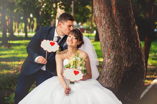 Couple de mariage mariée et le marié dans le parc avec des décorations de mariage nuages avec coeur