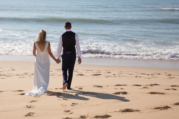 Couple de mariage mariée et le marié sur la plage de sable d'été à pied dans la côte de la mer